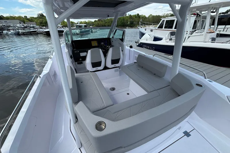 Slide: The Image of 2025 Axopar 29 Sun-Top boat interior with seating and helm, docked by the water. - 7