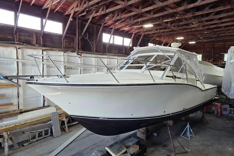 The Image of 2004 Carolina Classic 35 boat in a wooden garage, partially covered. - 0