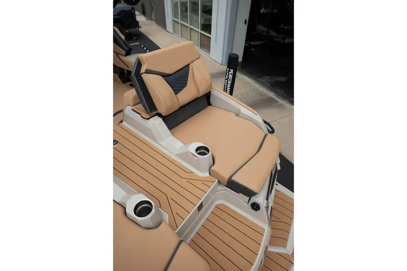Slide: The Image of 2026 MasterCraft X24 boat interior with tan and black seating, featuring cup holders. - 14