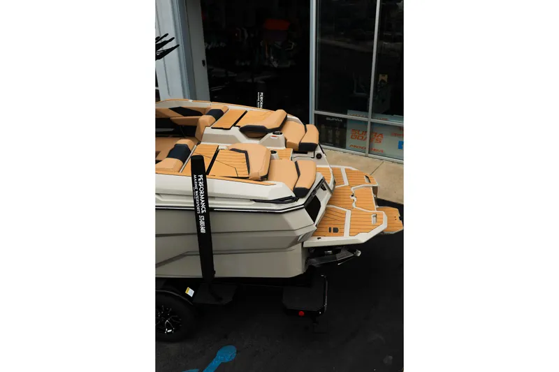 Slide: The Image of 2026 MasterCraft X24 boat with tan seating and swim platform, displayed indoors. - 6