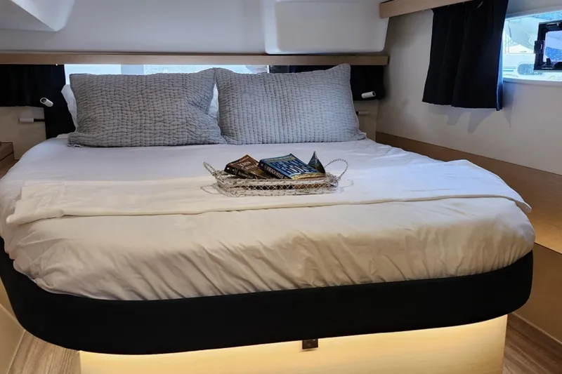 Slide: The Image of Cozy bedroom in 2017 Fountaine Pajot Lucia 40 catamaran with plush bedding and reading materials. - 10