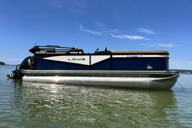 The Image of 2025 Lowe SS 210 WT pontoon boat on calm water under clear blue sky. - 0