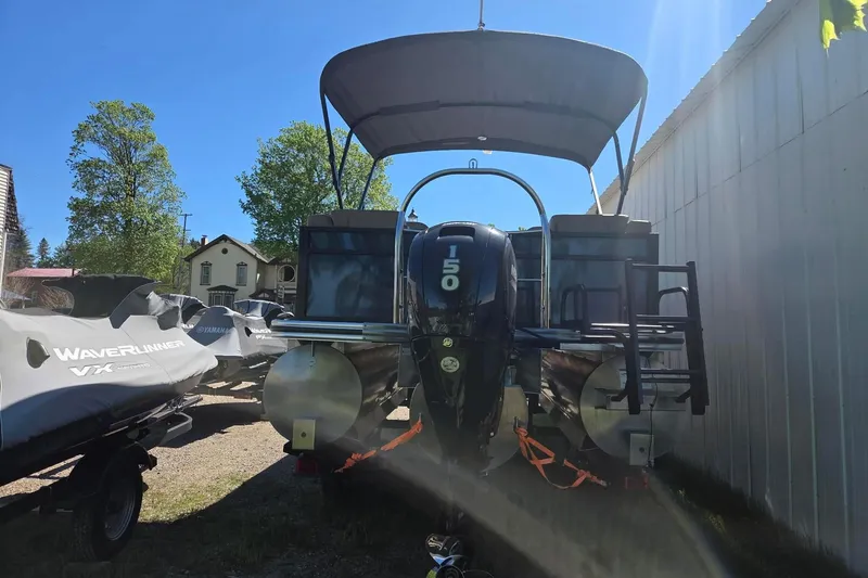 Slide: The Image of 2025 Lowe SS 210 WT pontoon boat with 150 HP engine, parked outdoors. - 10