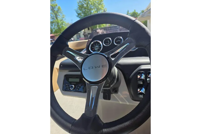 Slide: The Image of Steering wheel of 2025 Lowe SS 210 WT boat with dashboard controls. - 12