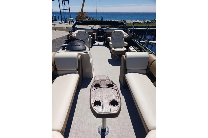 Slide: The Image of 2025 Lowe SS 210 WT pontoon boat interior with seating and table, docked by the water. - 14