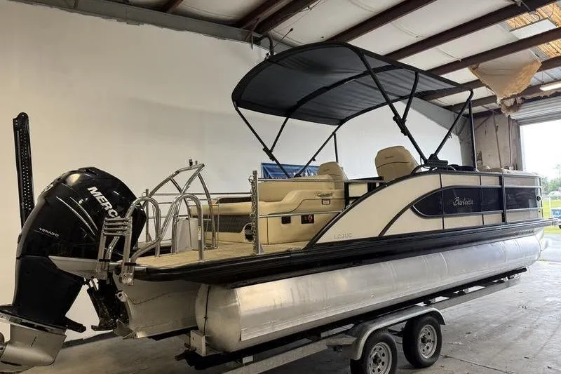 Slide: The Image of 2020 Barletta L23UC pontoon boat with canopy and Mercury outboard motor in a garage. - 3
