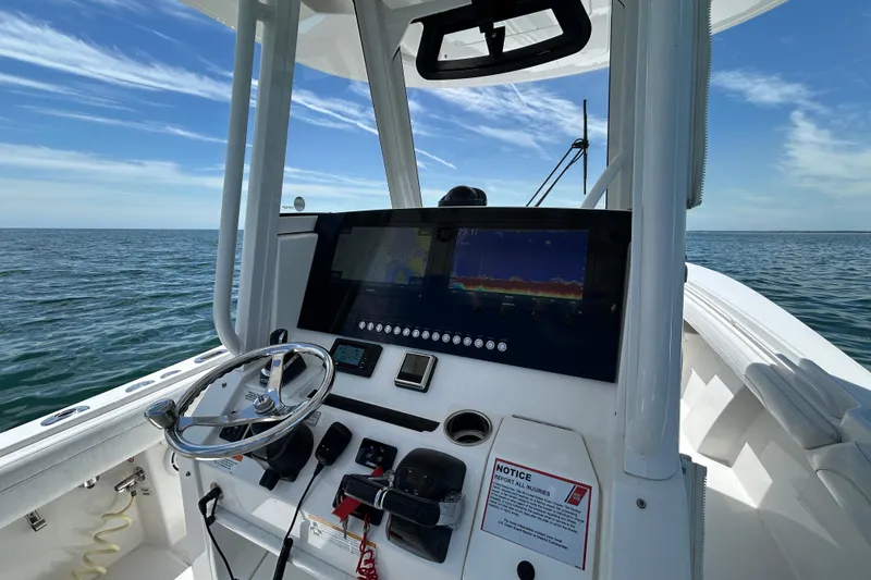 Slide: The Image of 2020 Regulator 28 boat dashboard with steering wheel and navigation screen on open water. - 5