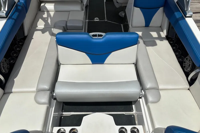 Slide: The Image of 2016 MasterCraft X26 boat interior with blue and white seating, cup holders, and speakers. - 11