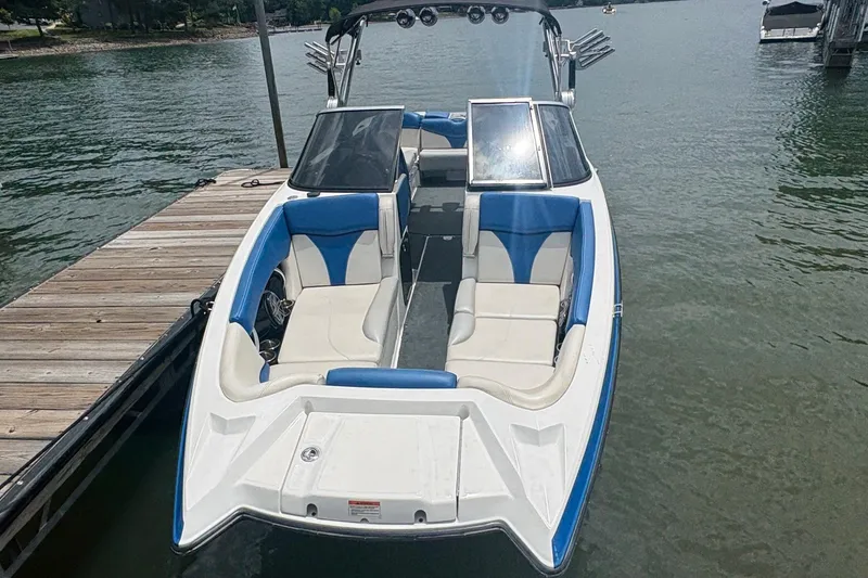 Slide: The Image of 2016 MasterCraft X26 boat docked on a lake, featuring blue and white seating. - 2