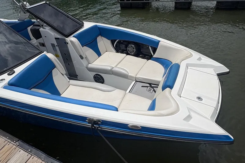 Slide: The Image of 2016 MasterCraft X26 boat with blue and white seating, docked on calm water. - 3