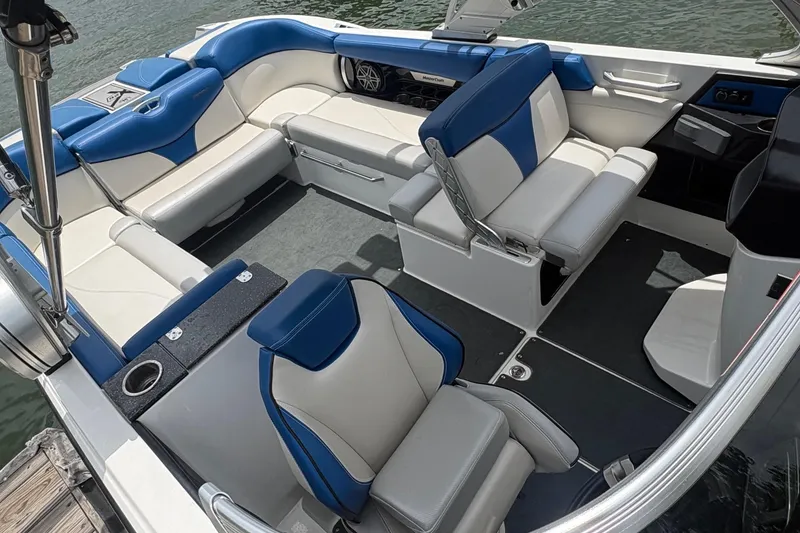 Slide: The Image of 2016 MasterCraft X26 boat interior with blue and white seating, docked on water. - 4