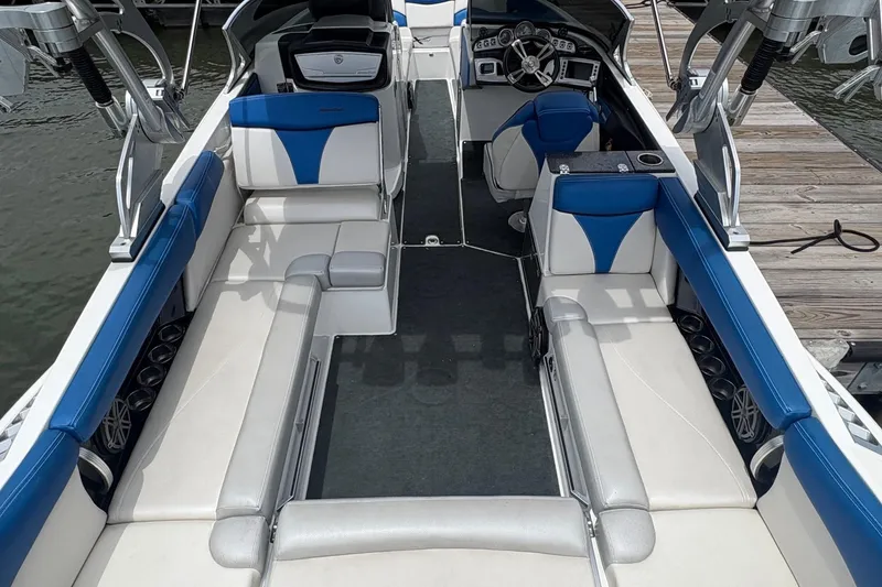 Slide: The Image of 2016 MasterCraft X26 boat interior with blue and white seating, docked by the water. - 8