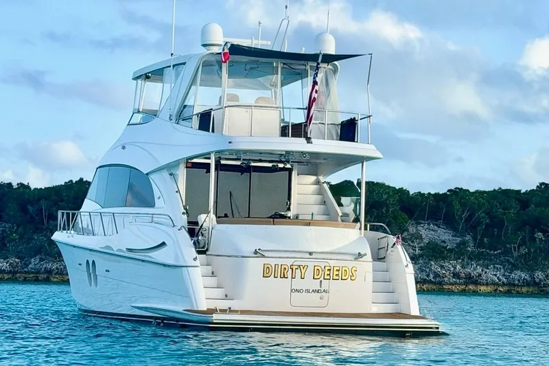 Slide: The Image of 2009 Hatteras 60 Motor Yacht on serene water, rear view with "Dirty Deeds" name. - 8