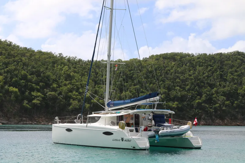 Slide: The Image of 2009 Fountaine Pajot Orana 44 catamaran anchored in a serene bay with lush greenery. - 1