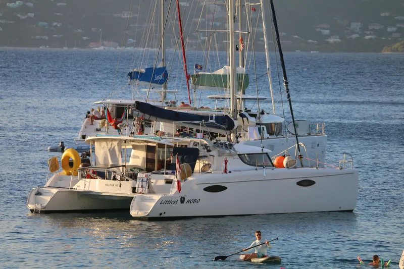 Slide: The Image of 2009 Fountaine Pajot Orana 44 catamaran anchored in serene waters with paddleboarders nearby. - 17