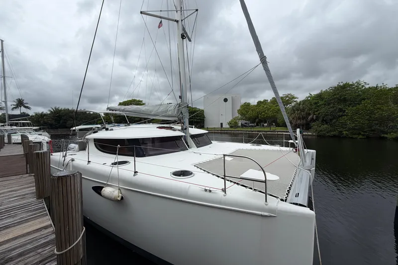 Slide: The Image of 2009 Fountaine Pajot Orana 44 catamaran docked by a wooden pier under cloudy skies. - 47