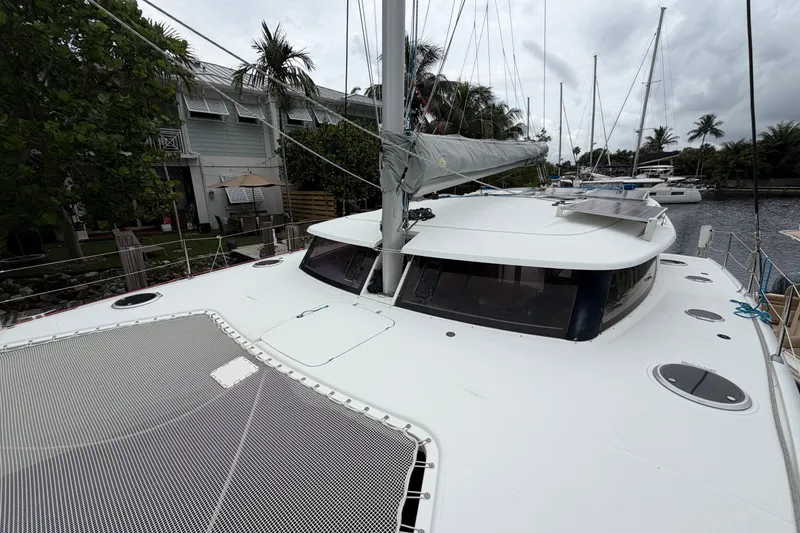 Slide: The Image of 2009 Fountaine Pajot Orana 44 catamaran docked near palm trees and waterfront homes. - 51
