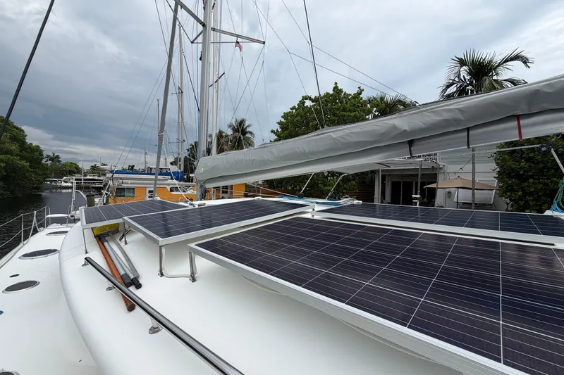 Slide: The Image of 2009 Fountaine Pajot Orana 44 catamaran with solar panels on deck, docked near lush greenery. - 52