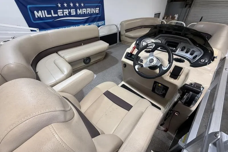 Slide: The Image of 2017 Sun Tracker Party Barge 22 DLX interior with beige seating and steering console. - 10