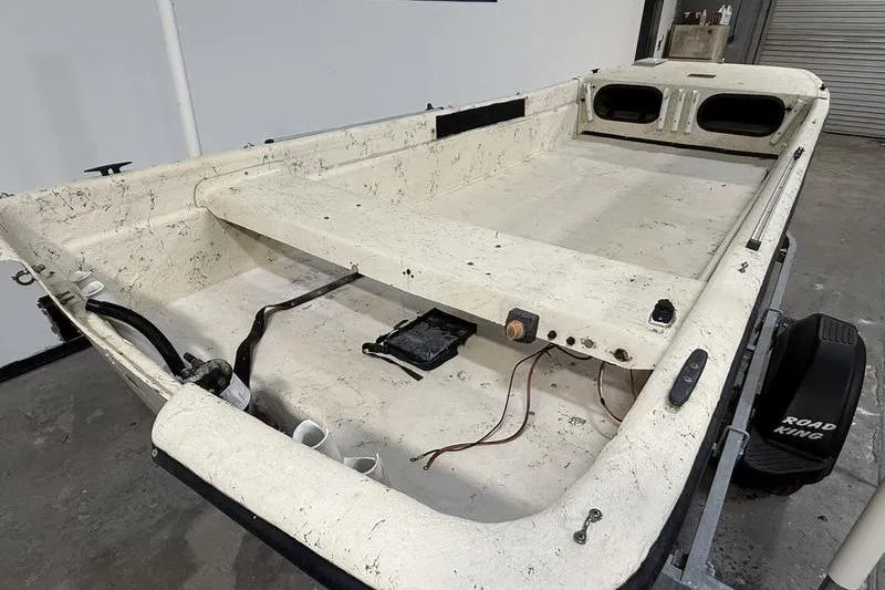 Slide: The Image of 1998 Carolina Skiff 1965 V boat interior, showing worn white deck and wiring. - 4