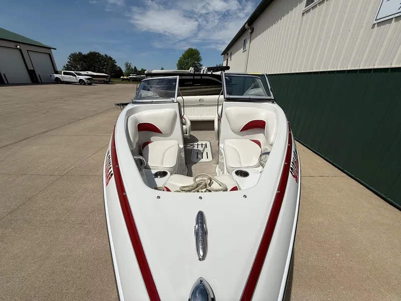 Slide: The Image of 2010 Crownline 180 BR boat with red accents on a parking lot. - 3