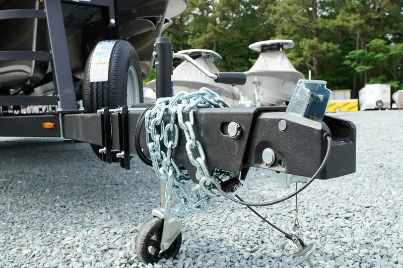 Slide: The Image of Trailer hitch of 2026 SunCatcher Fusion 324RC with safety chains on gravel lot. - 14