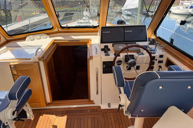 Slide: The Image of 2006 Sabre 38 Salon Express helm with dual screens, wooden accents, and blue seating. - 15