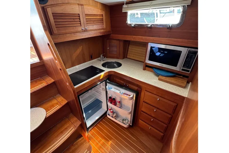 Slide: The Image of 2006 Sabre 38 Salon Express yacht kitchen with wood cabinetry, microwave, and compact fridge. - 22