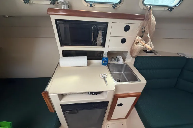 Slide: The Image of Compact galley in 2005 Albin 28 Tournament Express with sink, microwave, and storage. - 12