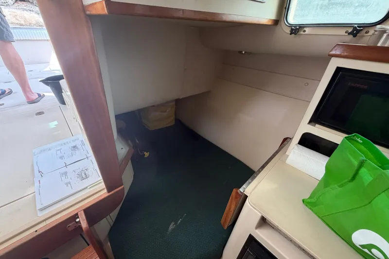 Slide: The Image of Interior cabin of 2005 Albin 28 Tournament Express boat with green bag and open manual. - 13