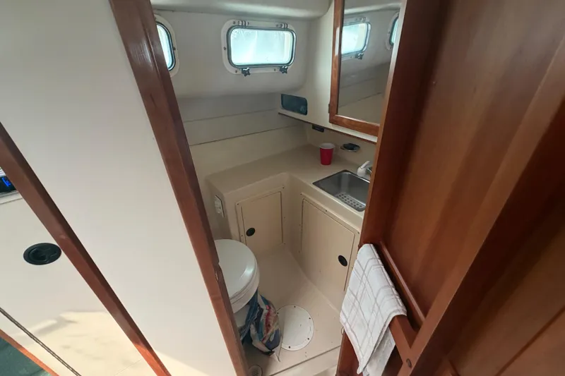 Slide: The Image of 2005 Albin 28 Tournament Express boat bathroom with sink, toilet, and wooden cabinetry. - 8