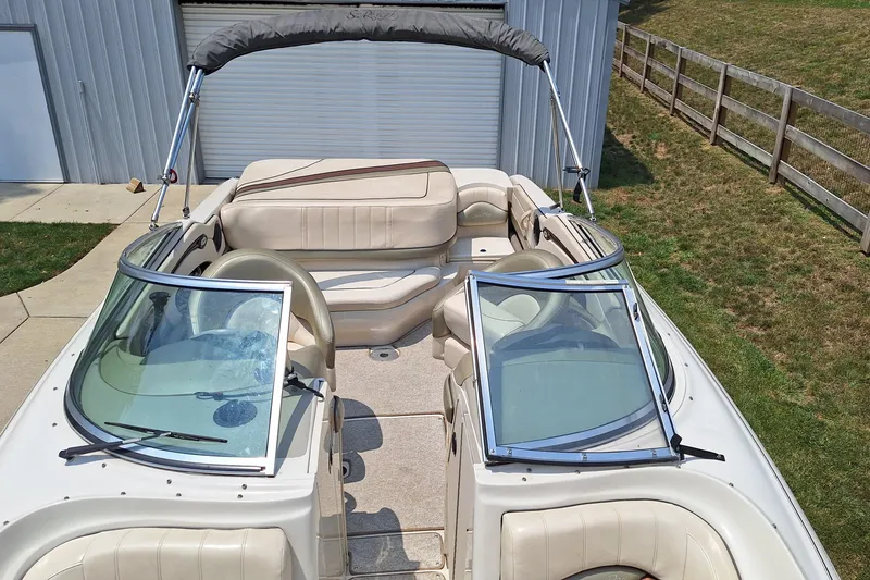 Slide: The Image of 2004 Sea Ray 240 Select boat with open seating and windshield, parked near a building. - 14