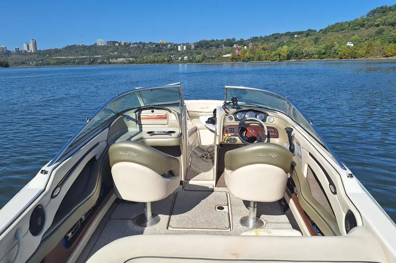 Slide: The Image of 2004 Sea Ray 240 Select boat interior on a scenic lake with lush green hills. - 28