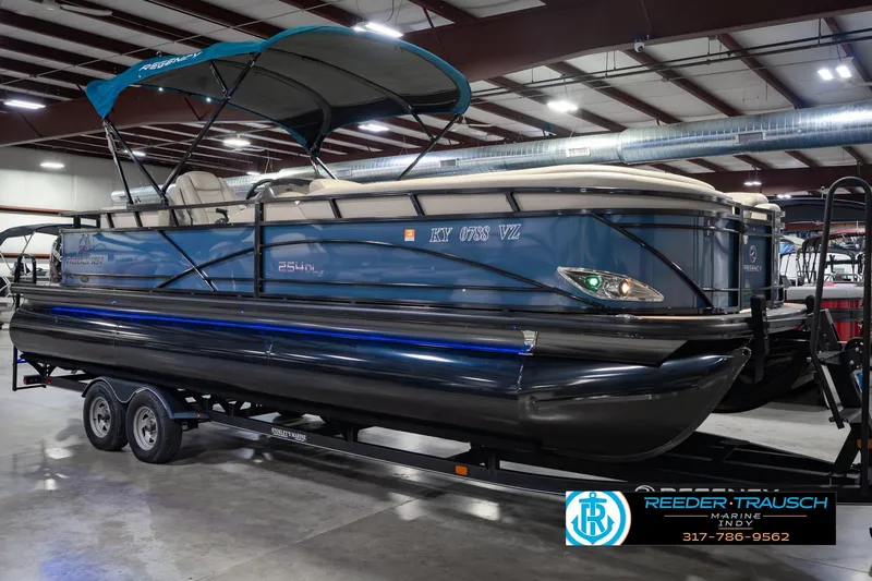 Slide: The Image of 2018 Regency 254 DL3 pontoon boat in showroom, blue exterior, on trailer. - 5