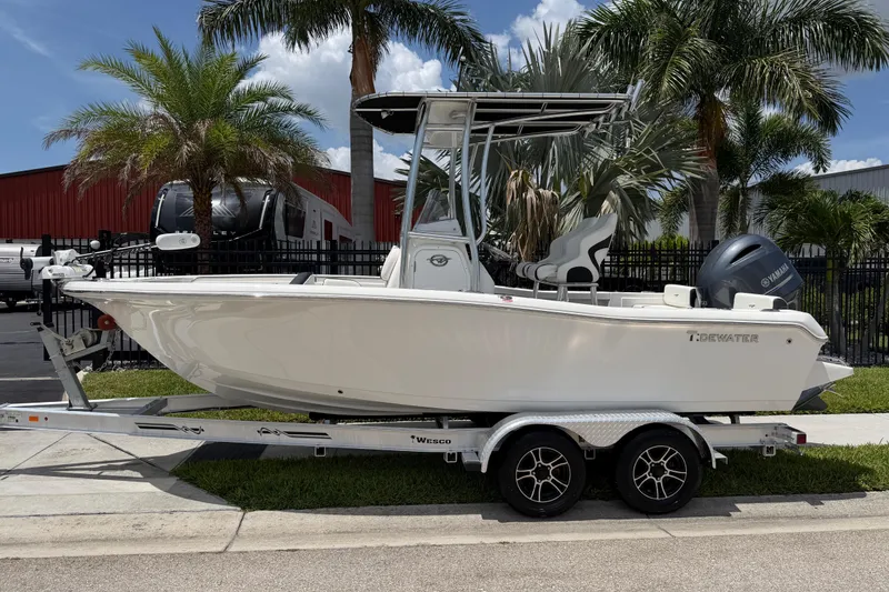 Slide: The Image of 2023 Tidewater 198 CC Adventure boat on trailer, parked near palm trees. - 2