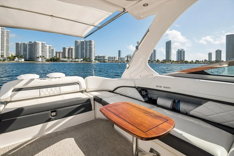 Slide: The Image of 2019 Regal 33 OBX boat interior with city skyline view, featuring luxurious seating and wooden table. - 7