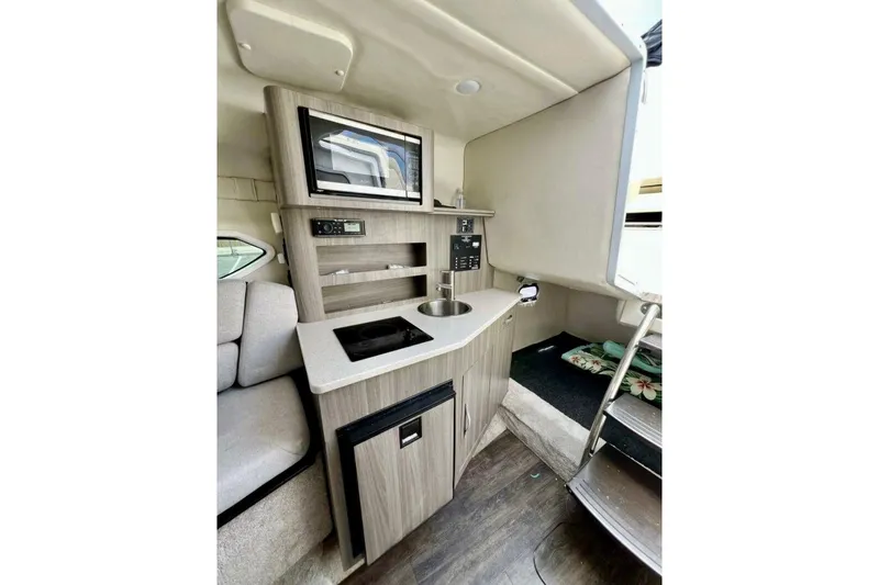 Slide: The Image of 2019 Regal 26 XO boat interior with kitchenette, microwave, and seating area. - 14