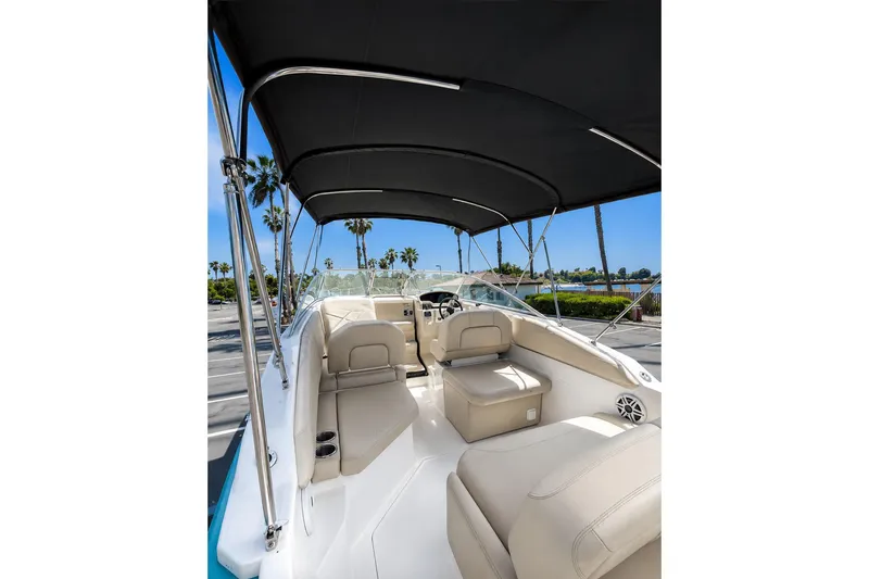 Slide: The Image of 2019 Regal 26 XO boat interior with canopy, featuring beige seating and waterfront view. - 5