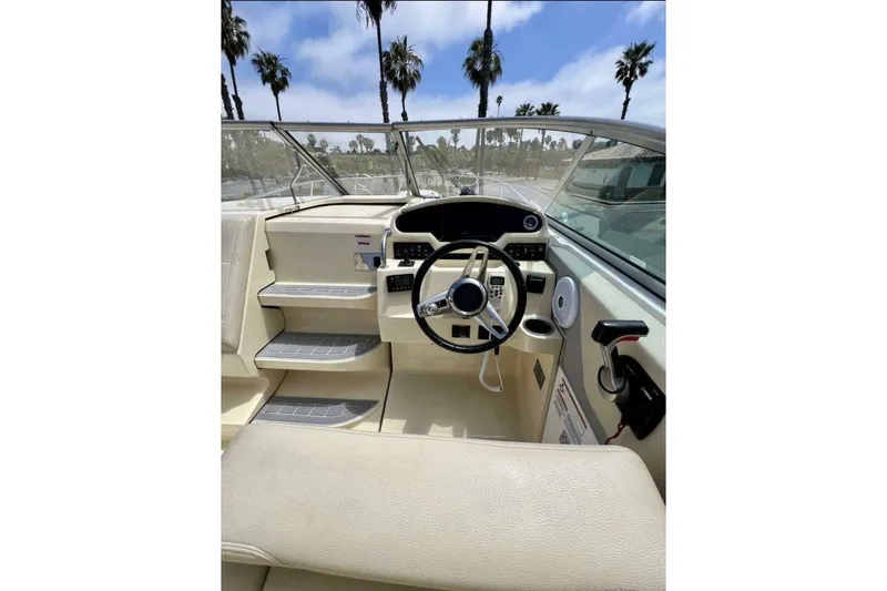 Slide: The Image of 2019 Regal 26 XO boat interior with steering wheel and dashboard, palm trees visible outside. - 8