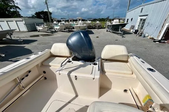 Slide: The Image of 2022 Grady-White Freedom 215 boat interior with seating and motor, docked outdoors. - 11