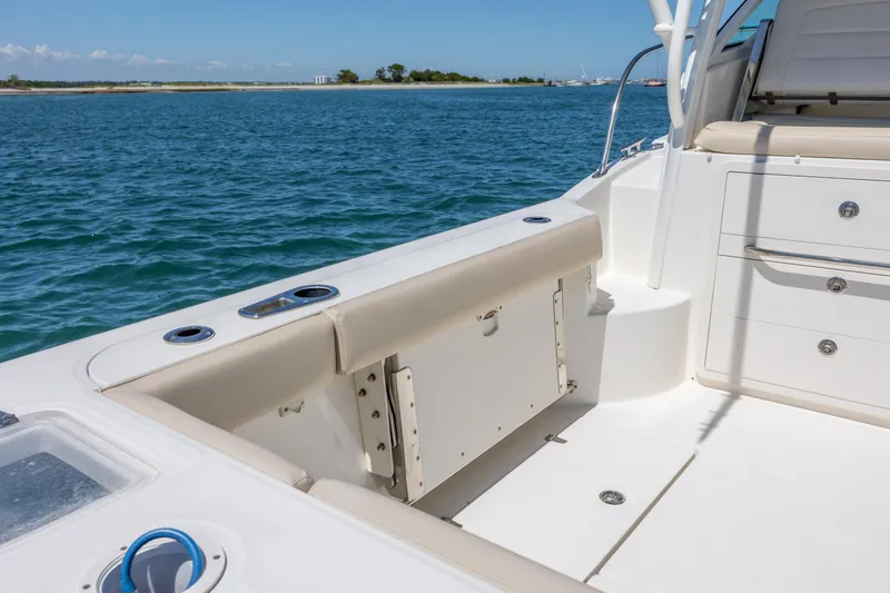 Slide: The Image of 2017 Boston Whaler 315 Conquest boat interior, featuring seating and storage, on calm blue waters. - 15
