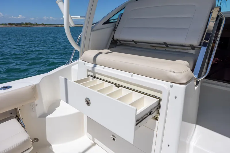 Slide: The Image of 2017 Boston Whaler 315 Conquest boat with open storage drawer, white seating, and ocean backdrop. - 16