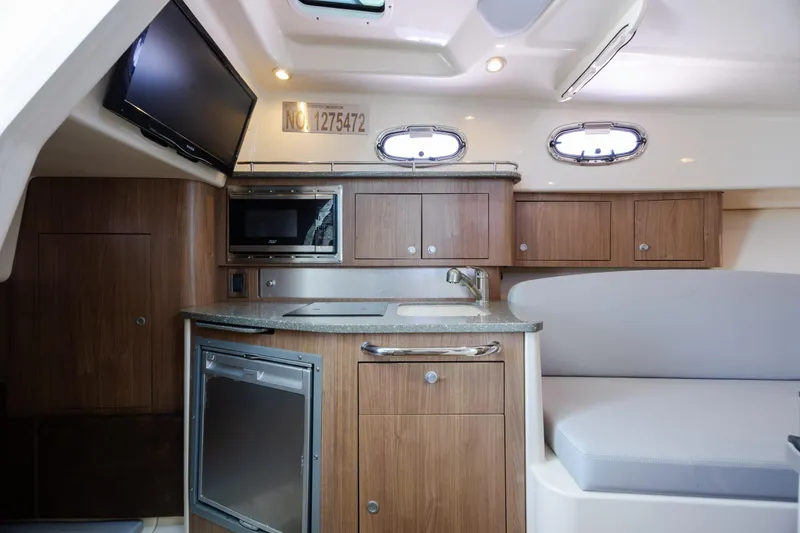 Slide: The Image of Interior of 2017 Boston Whaler 315 Conquest, featuring kitchenette and seating area. - 32