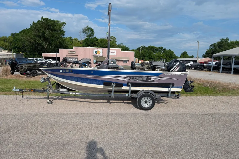 Slide: The Image of 2017 Lowe Fishing Machine 165SC Pro boat on trailer, parked outdoors. - 2