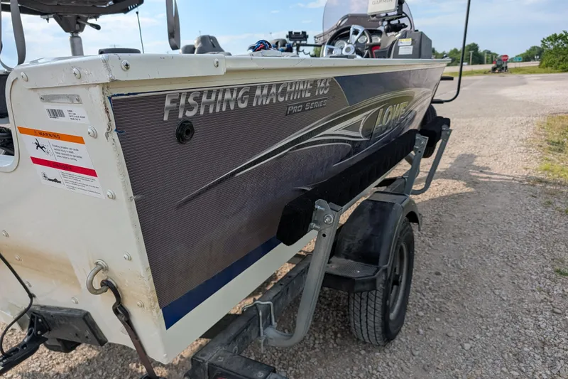 Slide: The Image of 2017 Lowe Fishing Machine 165SC Pro boat on trailer, parked on gravel road. - 6