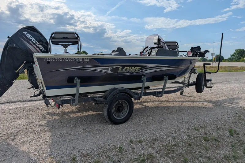 Slide: The Image of 2017 Lowe Fishing Machine 165SC Pro boat on trailer, parked outdoors. - 7