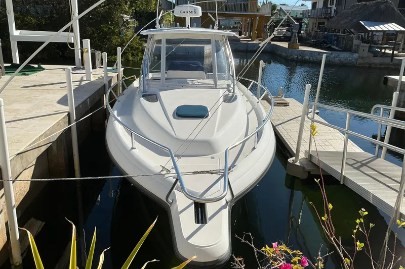 The Image of 2005 Intrepid 348 Walkaround boat docked in a marina with clear water. - 1