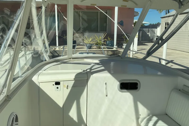 Slide: The Image of 2005 Intrepid 348 Walkaround boat interior with seating and helm, docked near a house. - 10