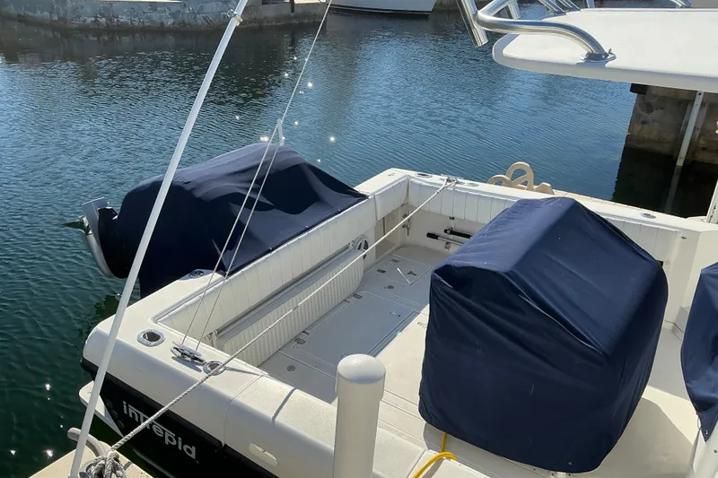 Slide: The Image of 2005 Intrepid 348 Walkaround boat docked, featuring covered seating and engines. - 4