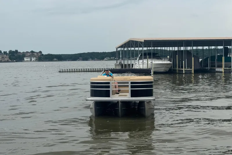 Slide: The Image of 2022 Harris Sunliner 250 pontoon boat on a lake near a marina. - 10